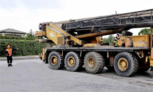 Photo shows worker signaling as a mobile crane is being moved into place.