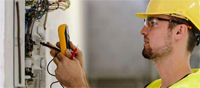 Photo shows electrician testing a circuit.